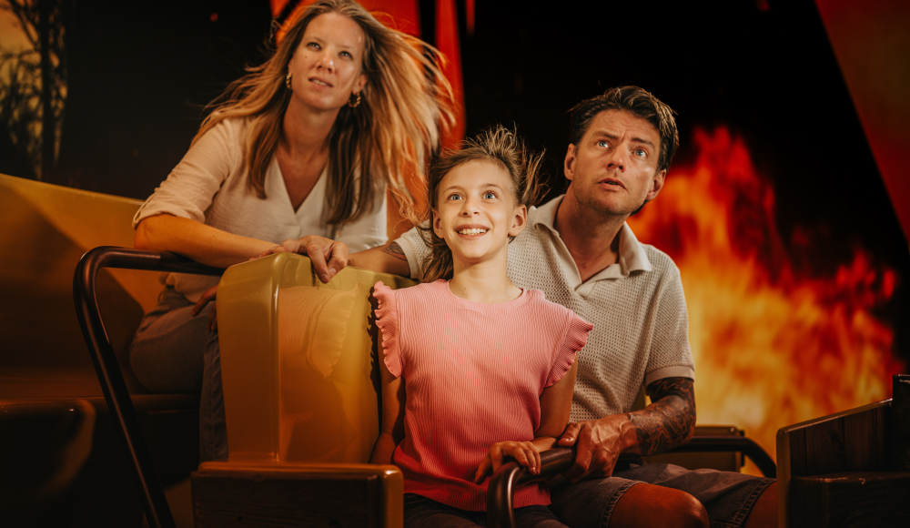 Vrouw, man en kind in een rijdende attractie met fel oranje licht en vuureffecten op de achtergrond Vrouw, man en kind in een rijdende attractie met fel oranje licht en vuureffecten op de achtergrond
