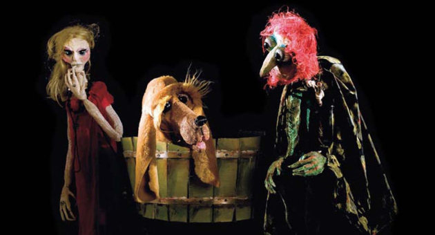 Drie poppen: vrouw, hond en heks in donkere setting