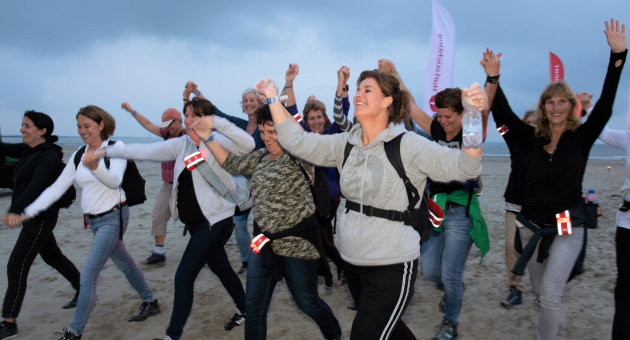 Wandelende mensen op het strand met hun armen in de lucht
