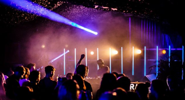 Feestende mensen met een dj op de voorgrond en discolampen