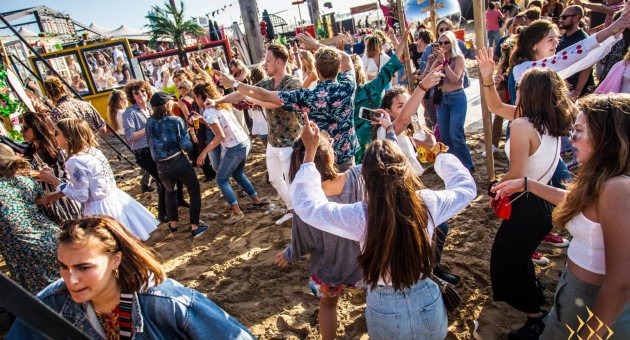 Mensen dansen op het strand bij Beachclub Indigo