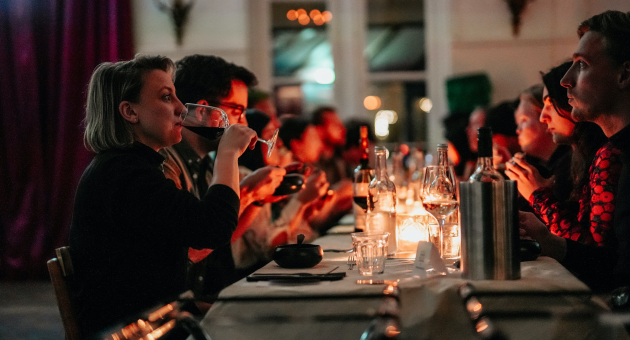 Gezellige dinersetting met kaarslicht, mensen drinken wijn en genieten van een sfeervolle avond