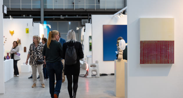 Bezoekers in een hal met kunstwerken tijdens Art The Hague
