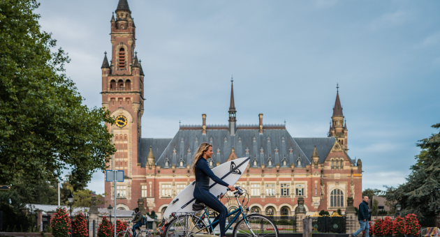 Surfer op de fiets voor het Vredespaleis 