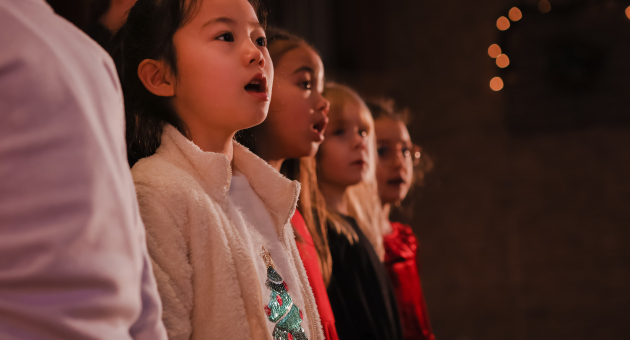 Jong meisje in het koor die kerst liederen zingt 