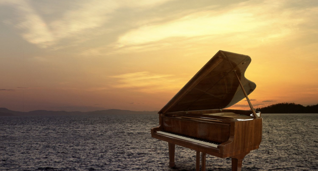 Een piano in het water met zonsondergang op de achtergrond