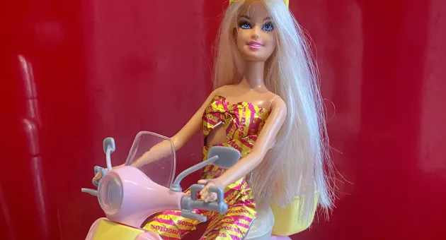 Barbie in recycle kleding op een scooter