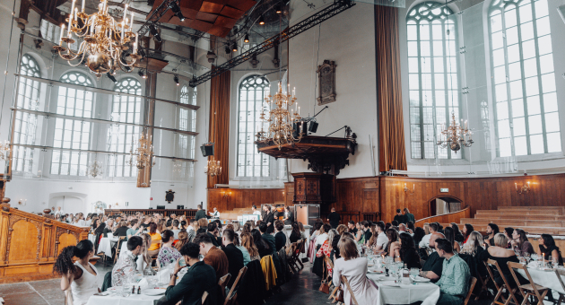 Pizza show sfeerimpressie met mensen aan gedekte tafels in Nieuwe Kerk Den Haag.