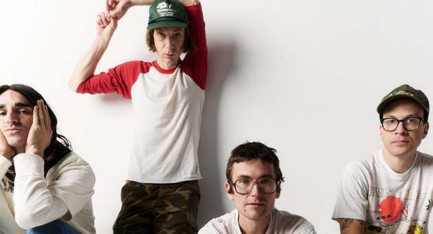 DIIV poseert in een minimalistische setting, met een nonchalante en eigenzinnige uitstraling. De bandleden stralen een mix uit van introspectie en rebelse energie.