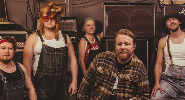 Portret van bluegrass band in jeans tuinbroeken met versterkers op de achtergrond.