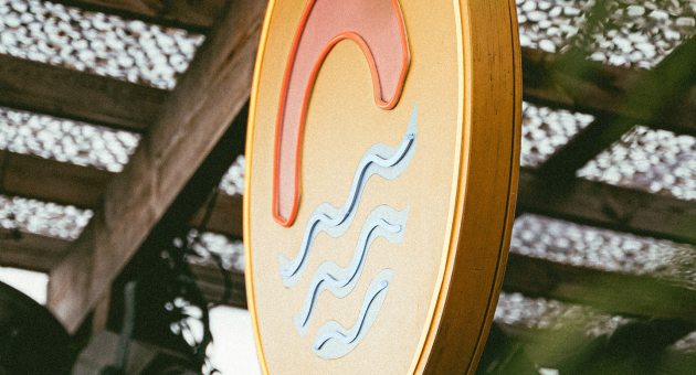 Rond uithangbord met golven bij strandlocatie.
