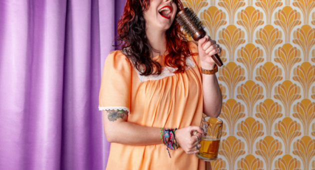 Vrouw in nachtjapon zingt met haarborstel en pul bier in slaapkamer setting, als slapstick vroegzat party