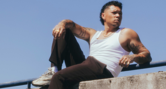 Portret van Ruben Annink nonchalant met een gespierde arm op een muur poserend.