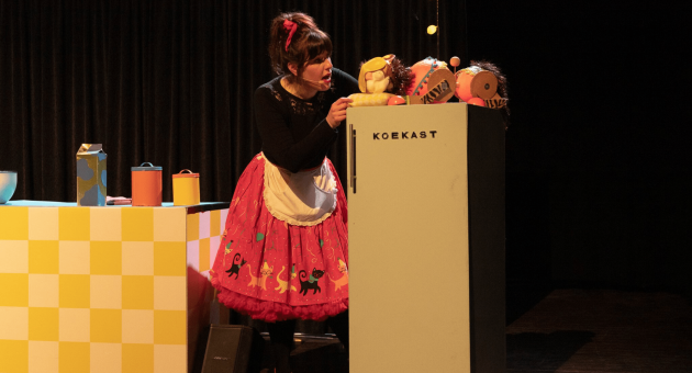 Vrouw in theaterkeuken opent 'koekast' met poppen (c) Laros & de jong beeldmakerij 
