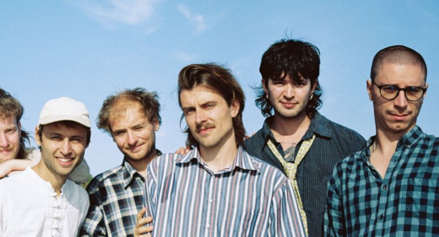 Groepsfoto van band Astronaut met op de achtergrond wolken, omdat je met hen meekijkt naar de aarde.