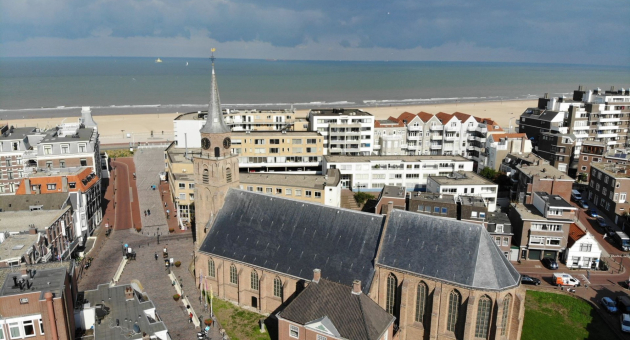 Boven aanzicht Oude Kerk Scheveningen met de strand en zee op de achtergrond.