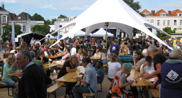 Prins Hendrikplein tijdens Zeeheldenfestival met tent, eettafels en gezellige sfeer.