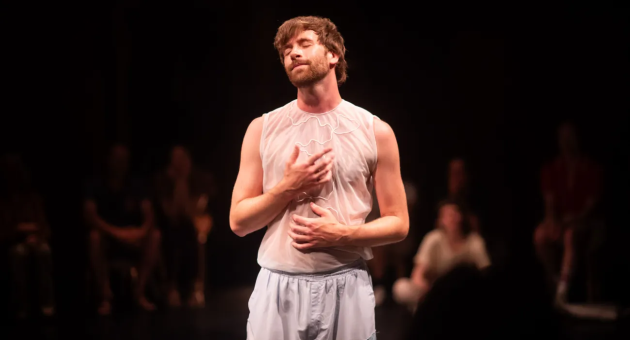 Philip Cahrpit staat op het podium in zijn theatervoorstelling Wanderlust. Hij draagt lichte losse kleding en heeft zijn ogen dicht. 