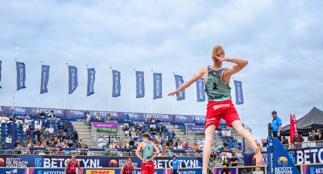Beachvolleyballer springt voor smash op het strand van Scheveningen