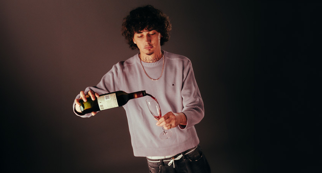 Portret van Def die een fles wijn inschenkt in een glas.
