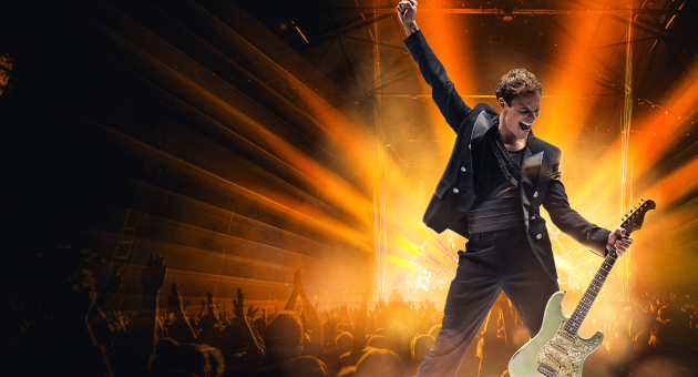 Rockzanger met gitaar voor juichend publiek op podium (c) We Will Rock You 