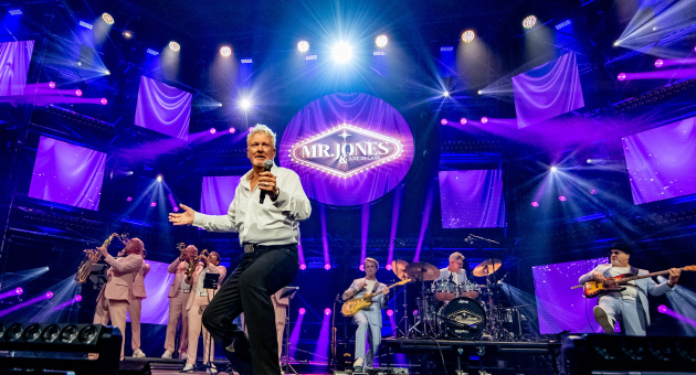 De leden van de tributeband Mr. Jones en Just in case staan op een paars verlicht podium. 