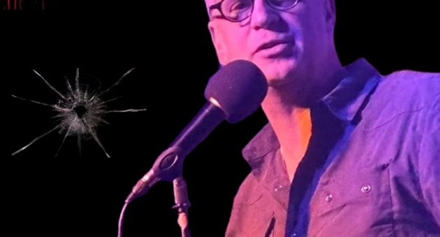 Man met bril zingt in microfoon op filmframe