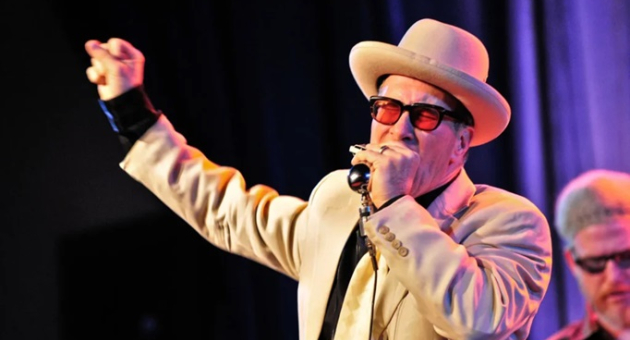 Zanger Mark Hummel in net pak zingend op podium.