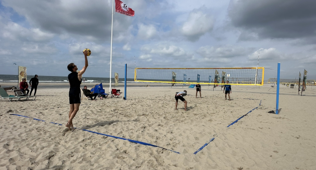 Beachsportfestival Kijkduin op het strand met man die volleybal raakt ter sfeerimpressie.
