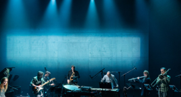 Het muziek ensemble Klang staat met hun instrumenten op een blauw verlicht podium