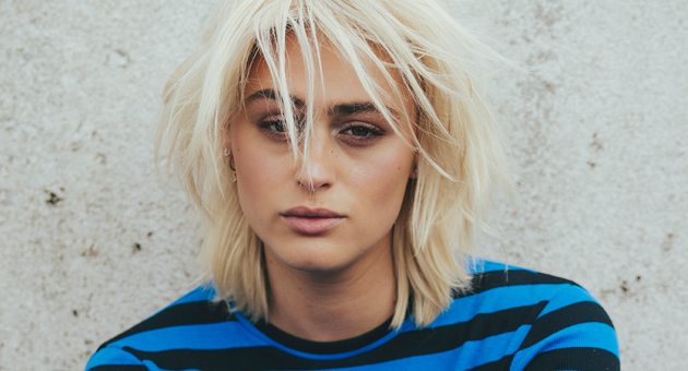 Portret van Bente serieus kijkend voor een betonnen muur. 