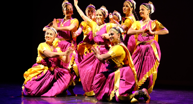 Groep dansers in kleurrijke Indiase kostuums poseert op een podium tijdens een klassieke dansvoorstelling