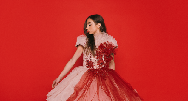 Soul en popzangeres Nona in rode galajurk voor rode achtergrond.