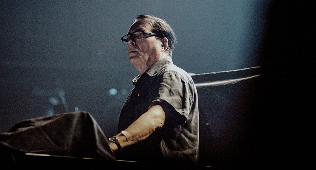 Muzikant van Kraftwerk Wolfgang Flür op het podium in donker maar met spotlight op zich gericht