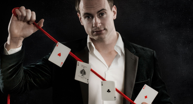 Een goochelaar in een chic pak voert een kaartentruc uit. 