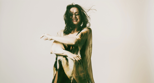 Isabelle Beernaert staat lachend voor een witte achtergrond in een dynamische pose