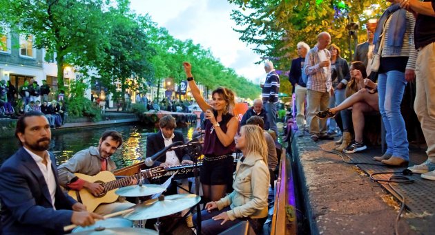 Live muziekoptreden op een boot in de gracht met publiek langs de kade