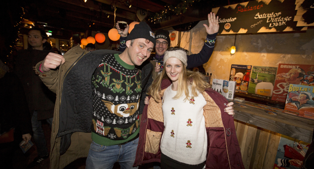 Vrolijke mensen met foute kersttruien in café