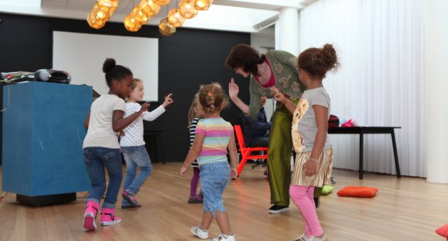 Kinderen dansen samen met een volwassene in een lokaal