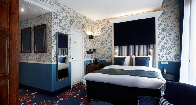 Stijlvolle hotelkamer met blauw-wit bloemmotief en luxe tweepersoonsbed
