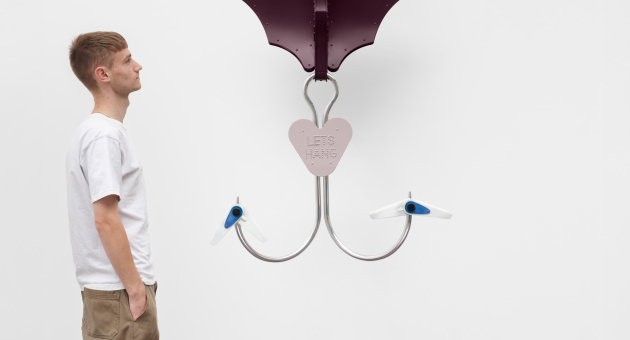 Een man kijkt naar een sculptuur van haken in de vorm van vleugels.