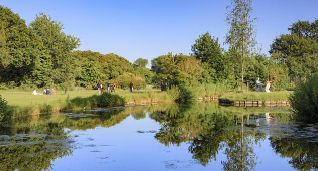 Menschen genießen einen sonnigen Tag in einem Park mit Wasserreflexion.