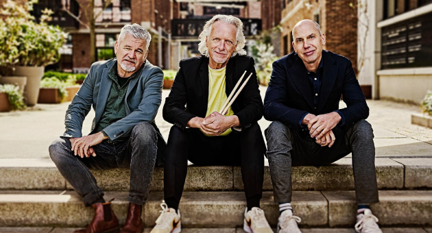 Drie mannen zitten op een trap in een stedelijke omgeving.