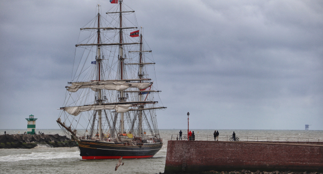 Een groot zeilschip vaart de haven van Scheveningen binnen.