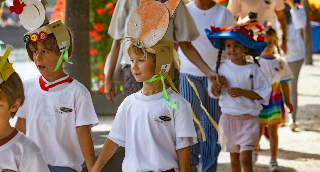 Groep kinderen gehouden handen en dragen kleurige hoedjes tijdens een festiviteit. ©From Our Dot fotografie