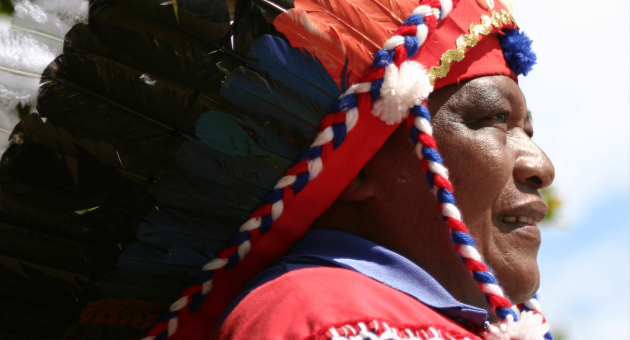 Man met een kleurrijk hoofddeksel en vest, in profiel
