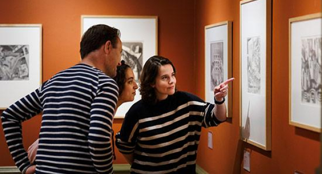 Drie mensen bekijken kunstwerken in een galerie.