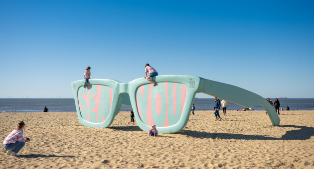 Large art installation of sunglasses reading 'SEA YOU' on Scheveningen beach.