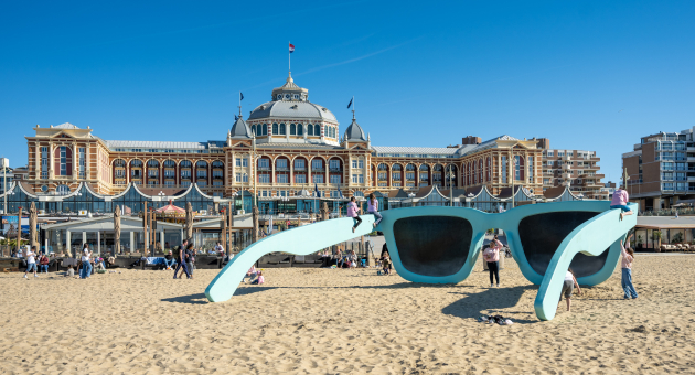 Mensen spelen bij een grote blauwe zonnebril op het strand