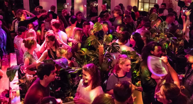 A crowded party venue with people dancing and socializing.